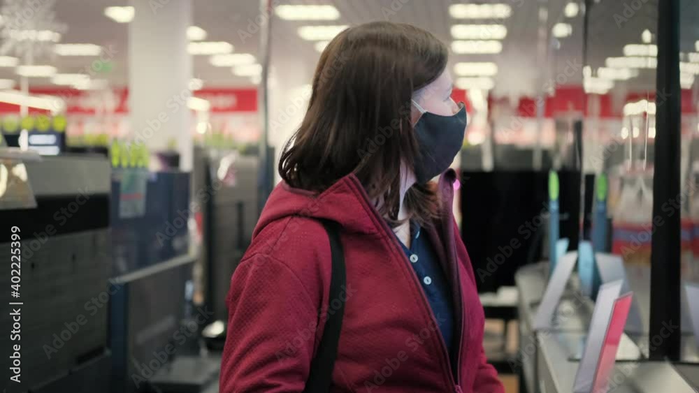 Caucasian girl in mask against virus dances in front of TV in store of electronic gadgets devices. Concept of big discounts, black Friday and holiday Caucasian girl in mask against virus dances in front of TV in store of electronic gadgets devices. Concept of big discounts, black Friday and holiday