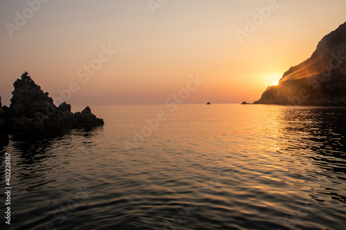 Silhouette of a man turned from behind while diving from a small marina on the sea. breathtaking sunset  golden hour.