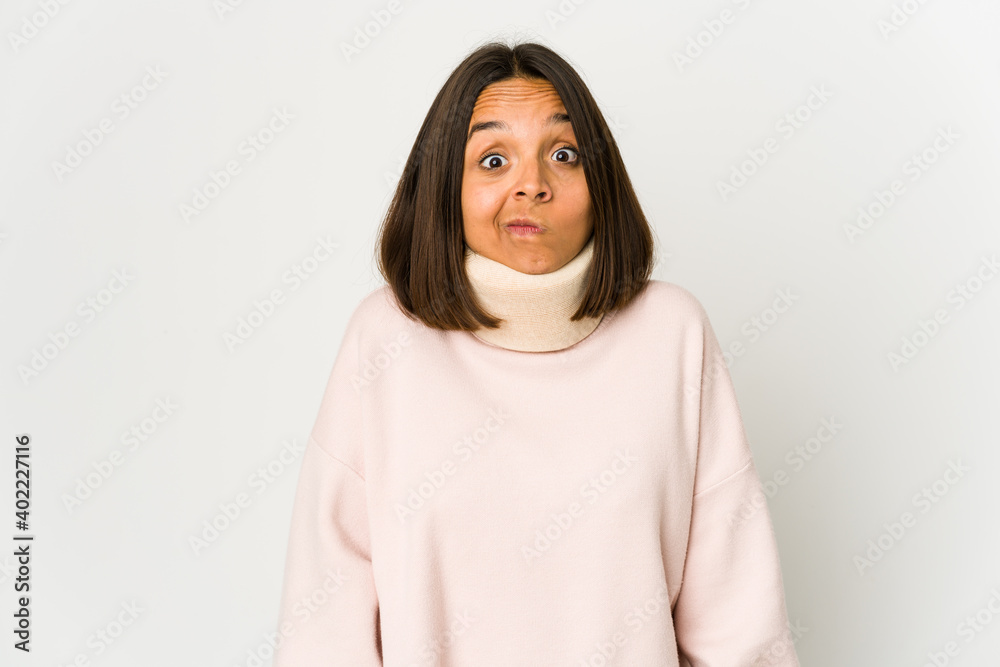 Young hispanic woman wearing a collar shrugs shoulders and open eyes confused. Young hispanic woman wearing a collar shrugs shoulders and open eyes confused.