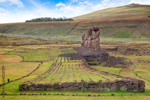 Stone structure and Moai statues at the Ahu Tongariki ceremonial center on Easter Island, against a blue sky. photo