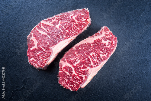 Raw dry aged wagyu roast beef steak offered as top view on a black board with copy space