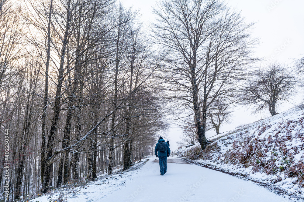 A young man walking on the path to climb Mount Aizkorri in Gipuzkoa. Snowy landscape by winter snows. Basque Country, Spain