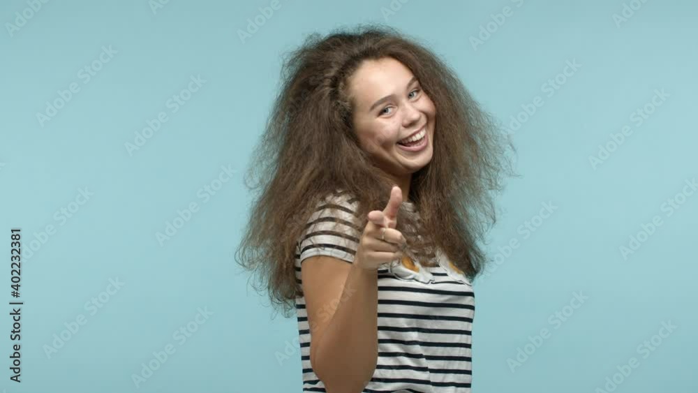 Slow motion of glamour girl dancing and pointing fingers at camera, need you, congratulating or praising good choice, standing over blue background Slow motion of glamour girl dancing and pointing fingers at camera, need you, congratulating or praising good choice, standing over blue background