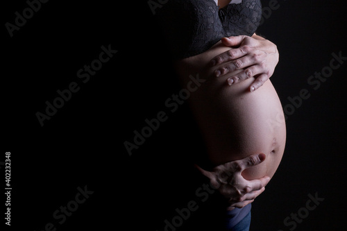Silhouette of a pregnant woman holding her pregnancy belly with copy space on the left