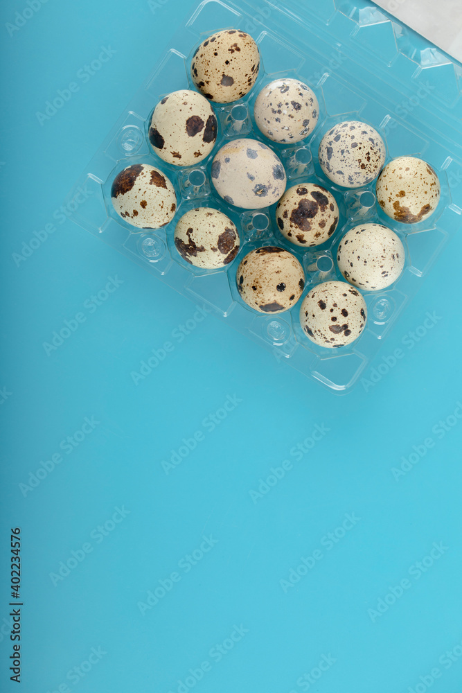 Container of quail eggs on blue background