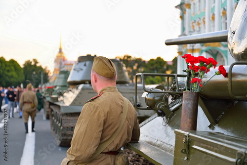ST.PETERSBURG, RUSSIA - AUGUST 08, 2017: Red carnations in a gun shell casing and a box with shells on a medium Soviet tank T-34-85 on the background of the Winter Palace and the Admiralty