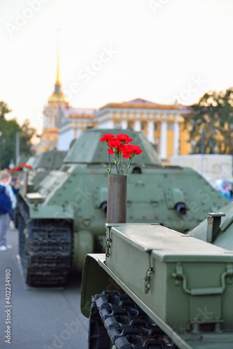 Red flowers in a gun cartridge on a medium Soviet tank T-34 on the background of the Admiralty