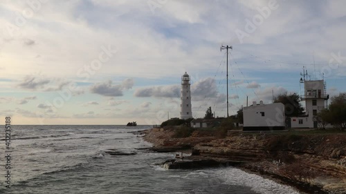 White lighthouse on the peninsula. Sunset. Waves at the white lighthouse.