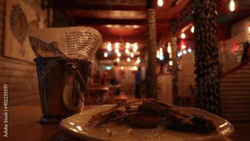 Fish bones on a plate. Fish on the table in the bar. Bar counter and bucket. Metal bucket with fish