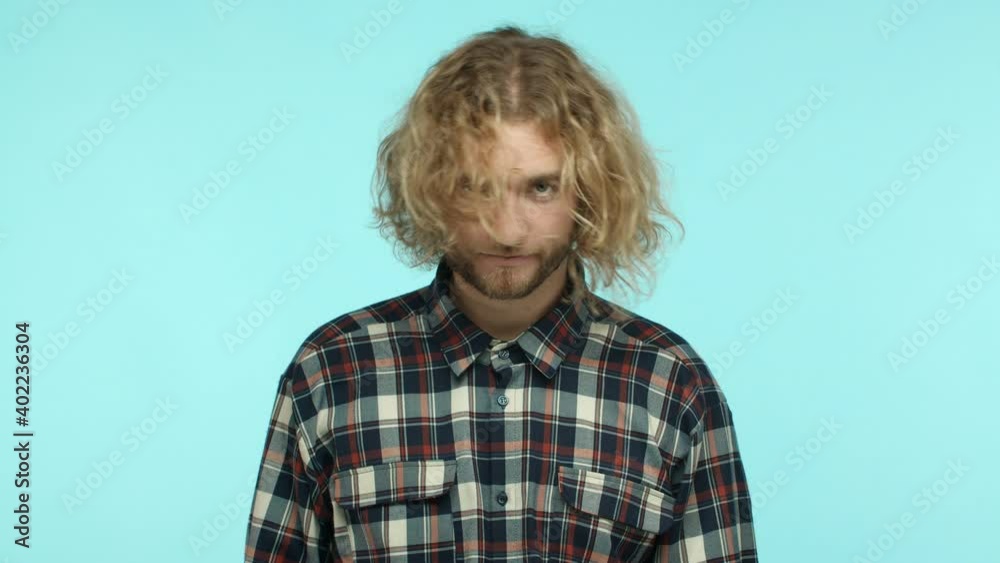 Annoyed or tired handsome man with long wavy blond hair, shooting himself in head sarcastic, showing hand gun gesture, standing over turquoise background Annoyed or tired handsome man with long wavy blond hair, shooting himself in head sarcastic, showing hand gun gesture, standing over turquoise background