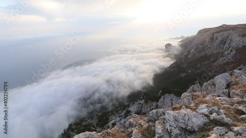 Clouds rise to the rocks. Fog over the rocks. The clouds move away from the rocks to the sea. Timelapse