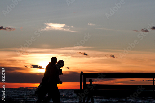 Silhouettes of people on the background of a stormy sky. Couples walk along the seashore in inclement weather. Strong wind. Evening. Estonia.