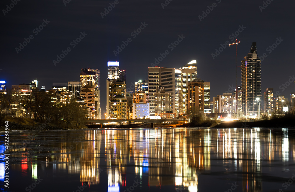 Downtown office building lights reflecting on the Bow River at night in Calgary Alberta Canada.
