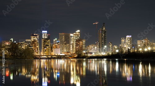 Downtown office building lights reflecting on the Bow River at night in Calgary Alberta Canada.