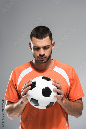 Brunette sportsman looking at football in hands isolated on grey © LIGHTFIELD STUDIOS