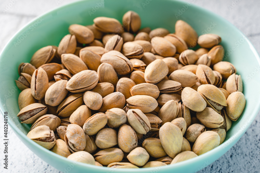 Close up on fresh salted roasted pistachios snack nuts in bowl with selective focus background Close up on fresh salted roasted pistachios snack nuts in bowl with selective focus background