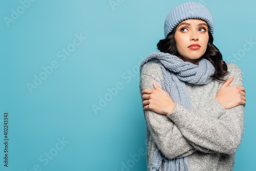 Εκτύπωση καμβά woman in winter outfit hugging herself while looking away isolated on blue