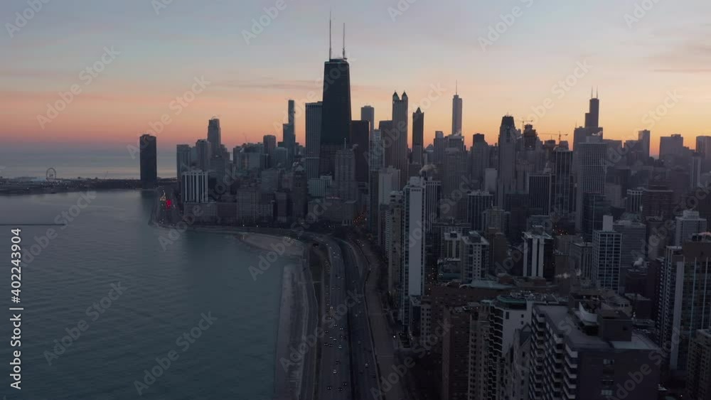 Aerial above Chicago skyline and road by Lake Michigan at sunset. Tall buildings with warm color sky Aerial above Chicago skyline and road by Lake Michigan at sunset. Tall buildings with warm color sky