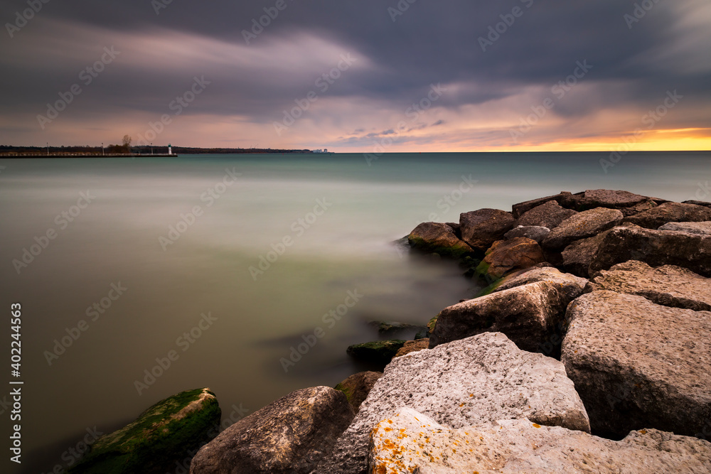 Long exposure photo of the rocky shores of Lake Ontario at sunrise