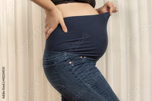 Pregnant woman with maternity pants with hight waist. Jeans for big tummy. Side view