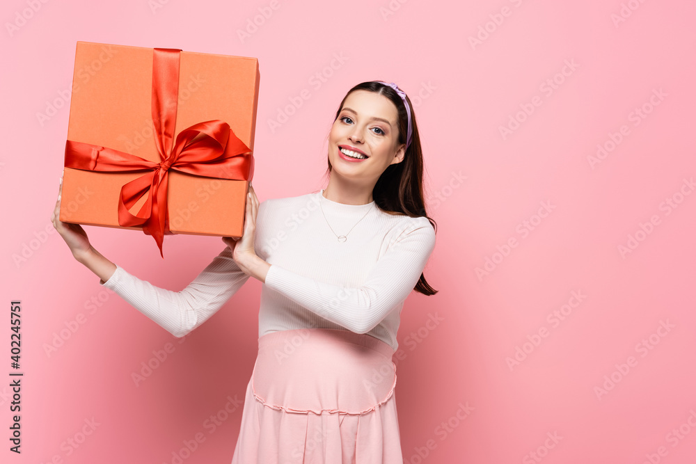 young pretty pregnant woman with gift isolated on pink young pretty pregnant woman with gift isolated on pink