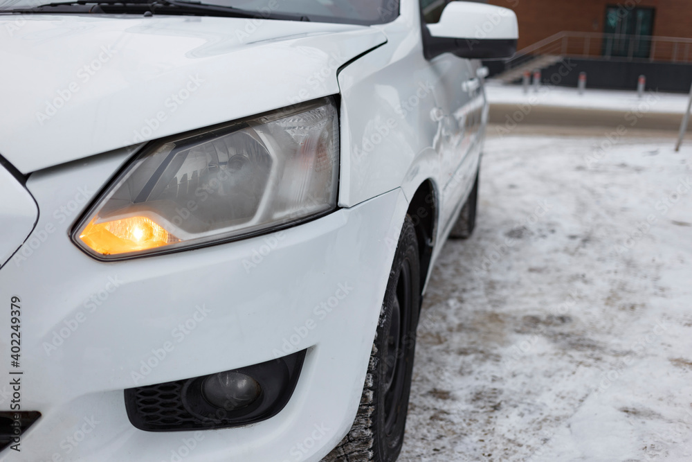 A white car stands in a city parking lot in winter close-up. blurred focus