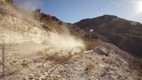 High speed driving quad 4x4 atv passing at dirt roads at Quartzsite, making a lot of dust where the sun shines through, AZ, USA. Pan. photo