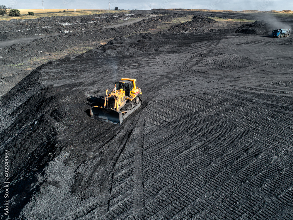 Bulldozer is pushing hard coal. Large coal heap. Bulldozer is pushing hard coal. Large coal heap.
