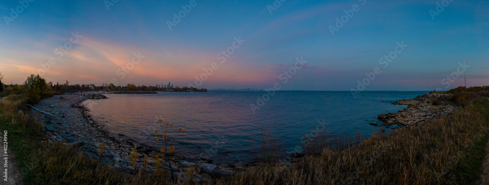 The city of Toronto is seen in the distance in this panoramic view across lake Ontario, taken from Colonel Samuel Smith Park in Toronto (Etobicoke), Ontario during a late evening sunset.