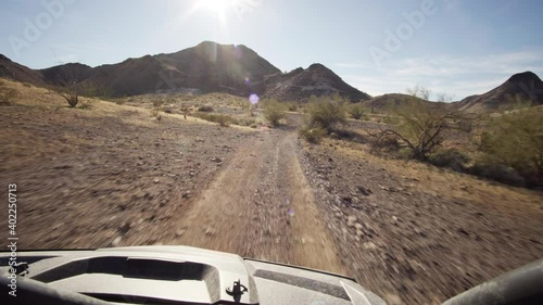 Driving on the slope of a mountain with a quad 4x4 atv towards the sun at dirt roads in the hills of Quartzsite, AZ, USA.