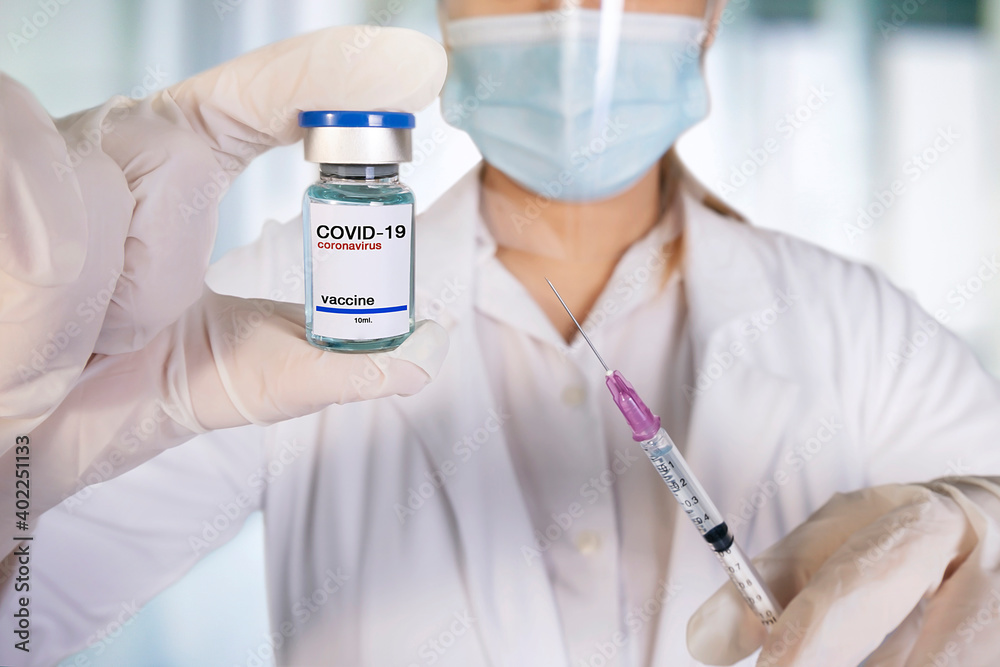 Syringe taking vaccine dose liquid from bottle on black background ,testing vaccine.