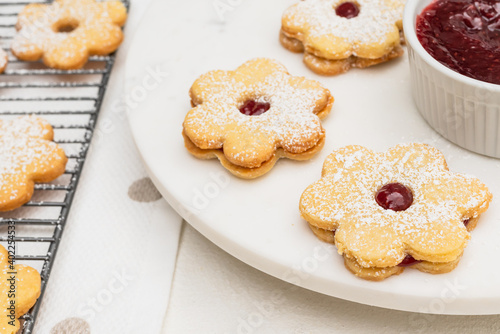 Flower shaped shortbread cookies filled with raspberry jam close up on white background