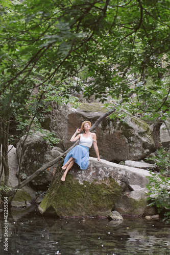 A girl in a blue skirt is walking in a beautiful forest