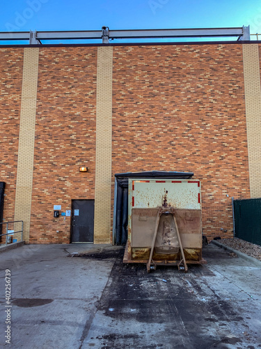 closed bay doors and garbage roll-offs outside an industrial complex