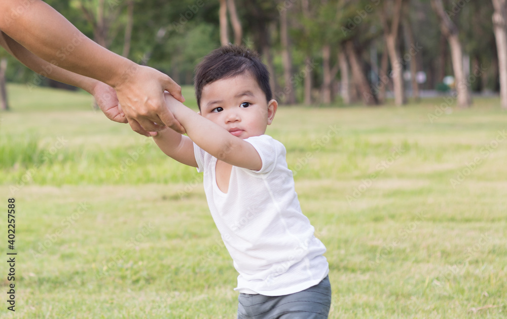 Father helping his son learn to walk on the lawn in city park. Father helping his son learn to walk on the lawn in city park.