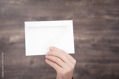 Male hand holding white mail envelope.