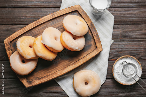 Tasty donuts and glass of milk on wooden background