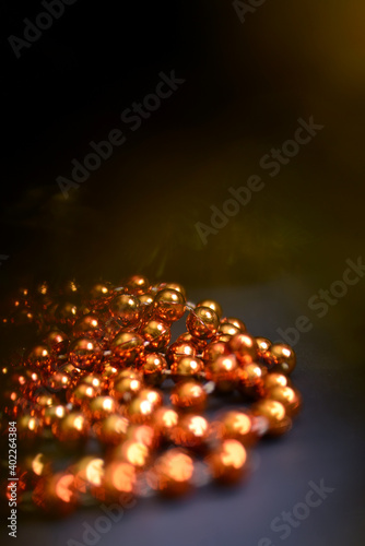 Orange beads with round beads for decorating the Christmas tree, close-up on a dark background. 