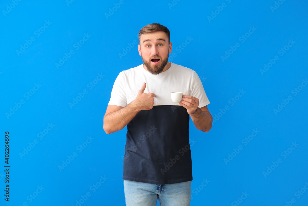 Surprised young man drinking hot coffee on color background Surprised young man drinking hot coffee on color background