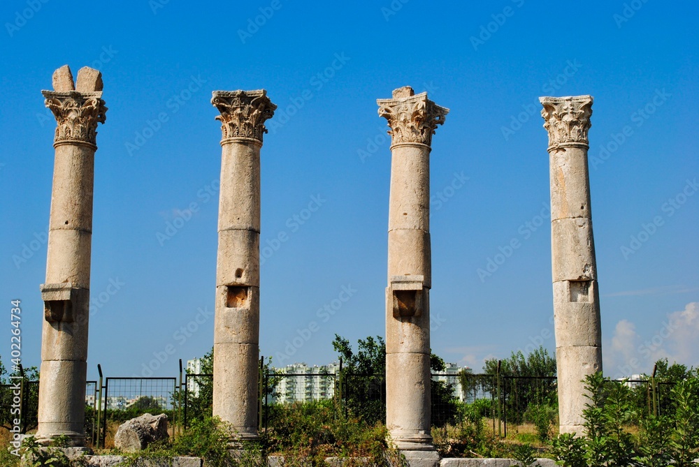 Corinthian columns of Roman colonnade in Mersin at the site of Soli Pompeipolis ancient city with distance new urban buildings background. Mersin Turkey. 