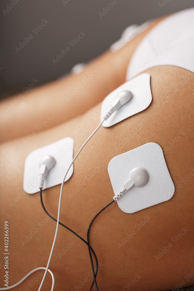 Myostimulation electrodes on the buttocks and legs of a woman in a beauty salon.