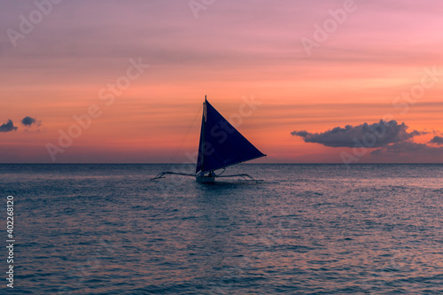 Beautiful sunset with a view of a local paraw saliboat in Boracy Island in the Philippines.  Travle and holiday. photo