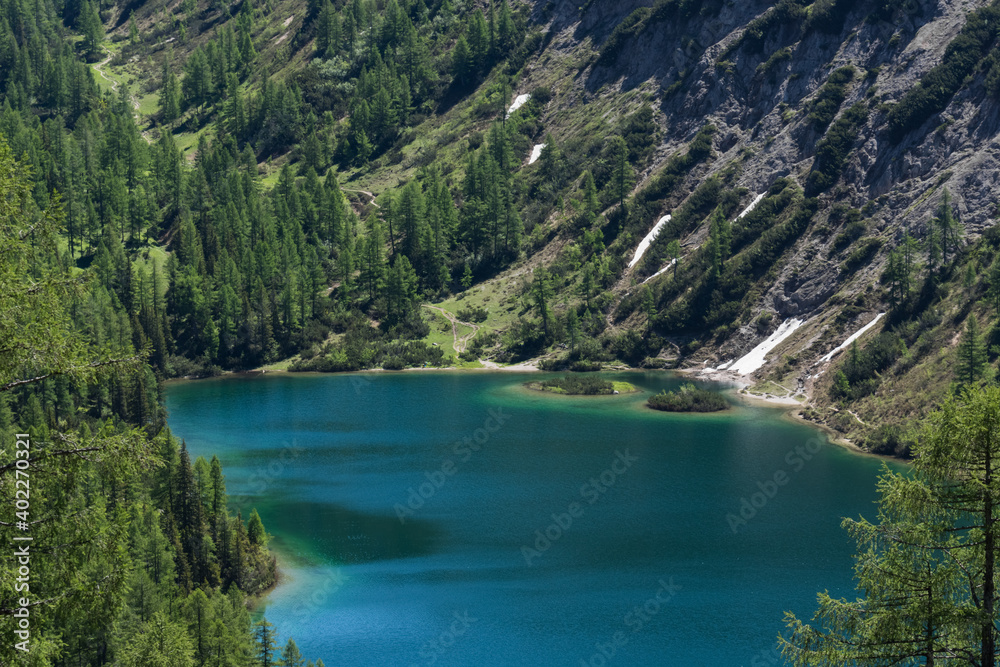 beautiful blue lake in the mountains with many green trees detail