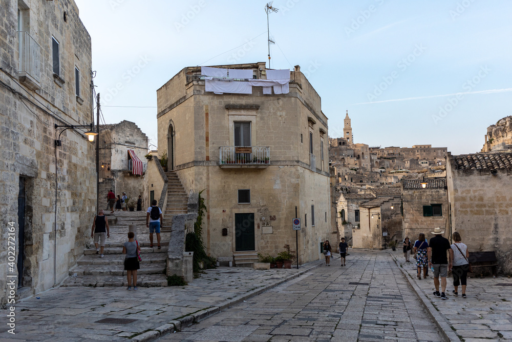  Tourists during a walk on Cobblestone street in the Sassi di Matera a historic district in the city of Matera. Basilicata. Italy