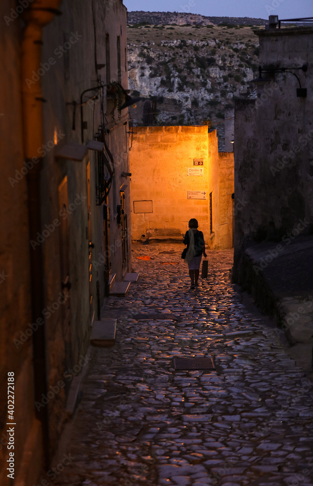 Woman during a walk on Cobblestone street in the Sassi di Matera a historic district in the city of Matera. Basilicata. Italy