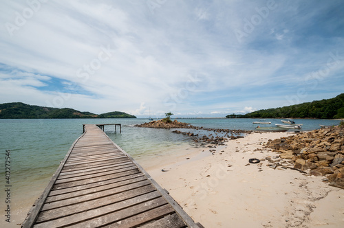Wooden jetty on over the beautiful borneo beach with blue sky and clouds