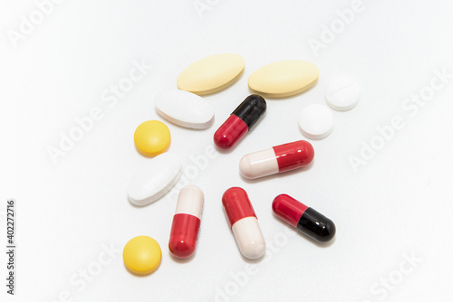 Red and white capsules  with some yellow and white tablet on white background