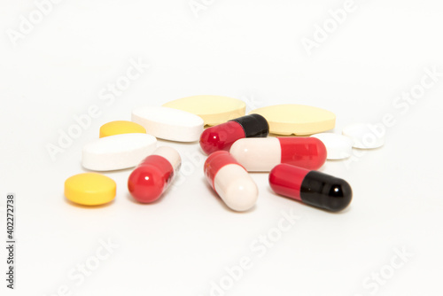 Red and white capsules  with some yellow and white tablet on white background