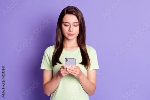 Photo portrait of calm serious female influencer browsing internet using smartphone isolated on bright violet color background