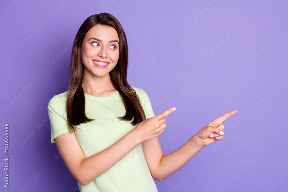 Photo portrait of cheerful happy girl smiling pointing with both hands looking at empty space isolated on bright violet color background Photo portrait of cheerful happy girl smiling pointing with both hands looking at empty space isolated on bright violet color background